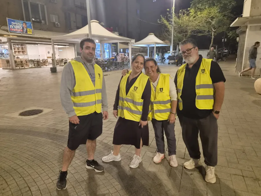 ארבעה מתנדבי סיירת הורים באפודים צהובים ברחוב בערב